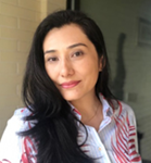 Uma mulher adulta e branca, cabelo preto levemente ondulado até a altura do peito, olhos escuros e sorrindo.