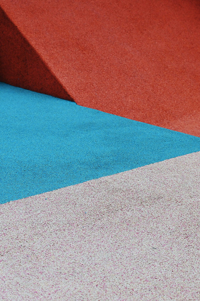 Composição gráfica com três faixas de cores dispostas em recortes diagonais. A faixa inferior é cinza, seguida por uma faixa de azul claro no meio e uma faixa de vermelha na parte superior. Composição gráfica com três faixas de cores dispostas em recortes diagonais. A faixa inferior é cinza, seguida por uma faixa de azul claro no meio e uma faixa de vermelha na parte superior.