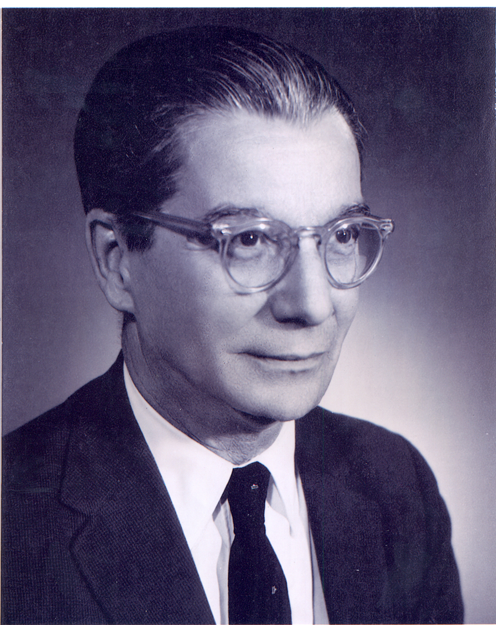 Fotografia em preto e branco de perfil de Anísio Teixeira, um homem com cabelos grisalhos e óculos redondos, usando terno e gravata pretos. Sua expressão é de um leve sorriso. Fotografia em preto e branco de perfil de Anísio Teixeira, um homem com cabelos grisalhos e óculos redondos, usando terno e gravata pretos. Sua expressão é de um leve sorriso.