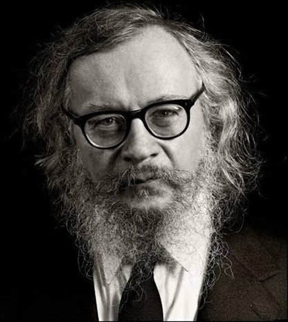 Fotografia em preto e branco de Jerzy Grotowski, um homem branco com cabelos, barba e bigode de tamanho médio e brancos, usando óculos e vestindo terno e gravata pretos. Fotografia em preto e branco de Jerzy Grotowski, um homem branco com cabelos, barba e bigode de tamanho médio e brancos, usando óculos e vestindo terno e gravata pretos.
