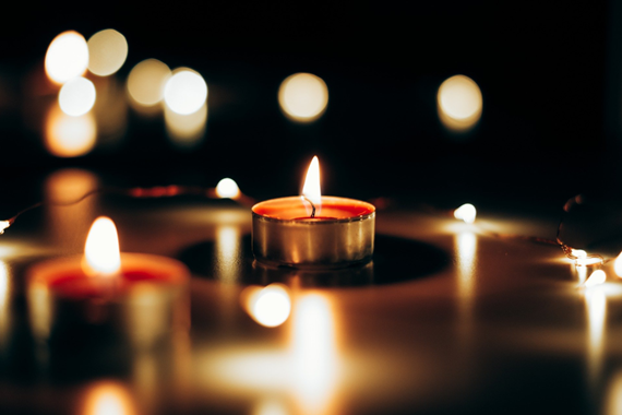 Fotografia de uma vela acesa em um fundo escuro e desfocado Fotografia de uma vela acesa em um fundo escuro e desfocado