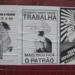 Fotografia de uma parede de azulejos vermelhos com três pôsteres colados. O primeiro mostra um desenho de uma mãe com o filho nos braços, que sangra de um ferimento na região abdominal, onde se lê: Nossos filhos e filhas sangram junto com nossa esperança de uma sociedade justa. O segundo pôster tem uma imagem do personagem Mr Burns dos Simpsons rindo, onde se lê: Quanto mais você trabalha, mais rico fica o patrão. O terceiro pôster, em estilo agitprop, mostra um desenho de um homem segurando uma chave inglesa, onde se lê: Trabalhador defenda seus direitos! Marcha antifascista, Praça da Sé, 13 de maio, 12h.