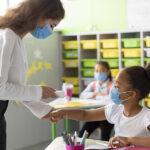 Fotografia de uma professora medindo a temperatura de uma aluna em uma sala de aula.Fotografia de uma professora medindo a temperatura de uma aluna em uma sala de aula.