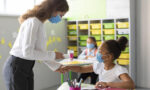 Fotografia de uma professora medindo a temperatura de uma aluna em uma sala de aula.Fotografia de uma professora medindo a temperatura de uma aluna em uma sala de aula.